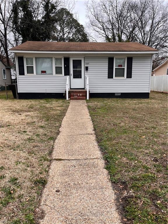 view of front of home featuring entry steps, fence, and a front lawn