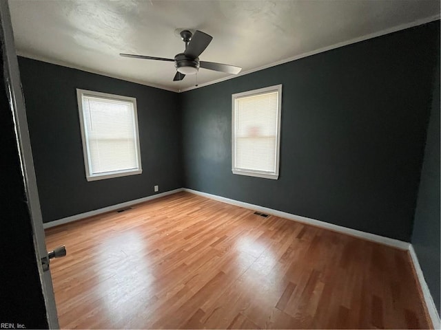 empty room with a healthy amount of sunlight, baseboards, and visible vents