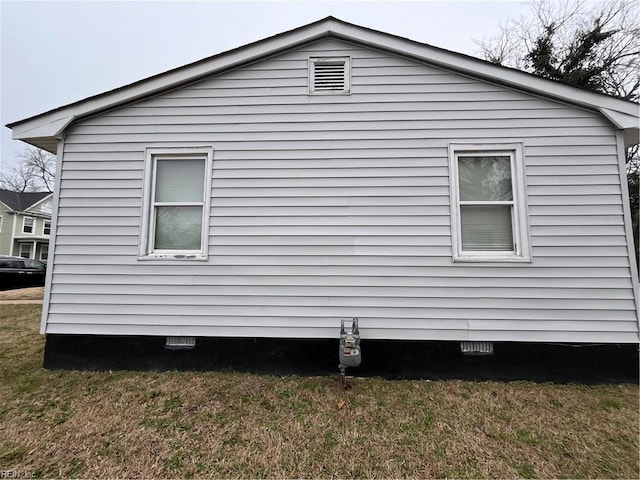 view of side of property with crawl space and a lawn