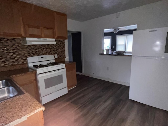 kitchen with white appliances, decorative backsplash, dark wood finished floors, and under cabinet range hood