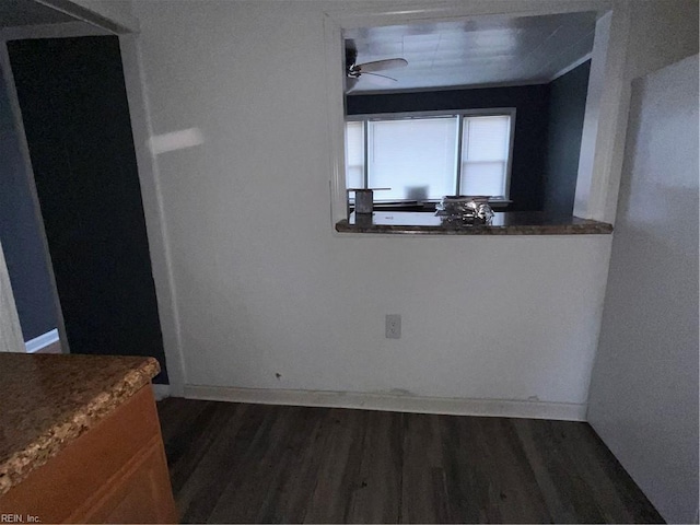 unfurnished dining area with dark wood-type flooring, a ceiling fan, and baseboards