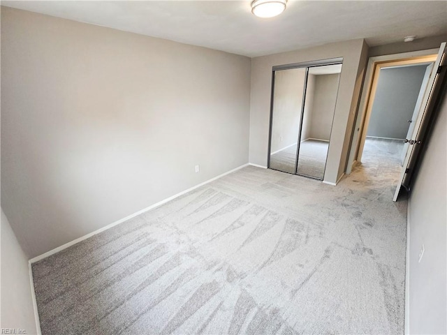 unfurnished bedroom featuring baseboards, a closet, and light colored carpet