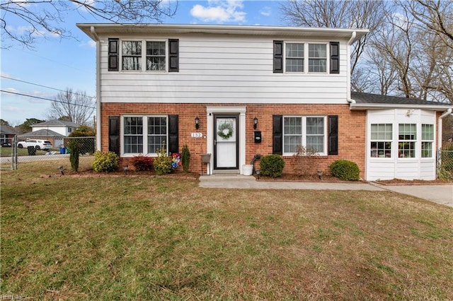 colonial home with a front yard, brick siding, and fence