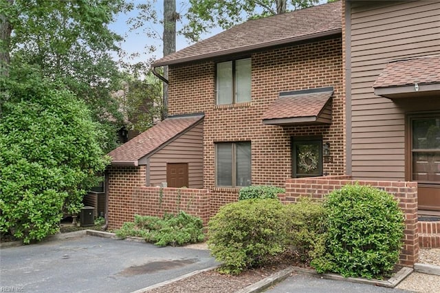 view of side of home with brick siding and roof with shingles