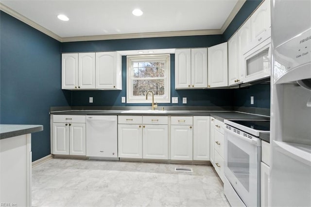 kitchen with white appliances, a sink, white cabinets, dark countertops, and crown molding