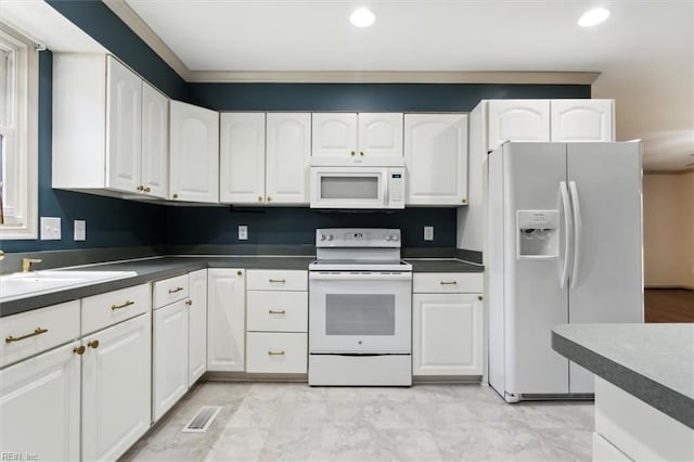 kitchen with white appliances, dark countertops, recessed lighting, and white cabinets