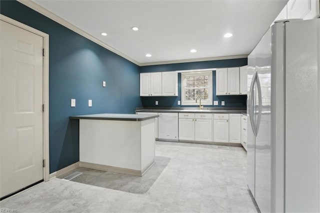 kitchen with crown molding, dark countertops, white cabinets, a sink, and white appliances