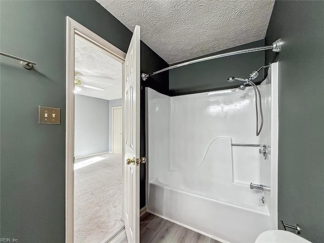 bathroom featuring a ceiling fan, tub / shower combination, a textured ceiling, and wood finished floors