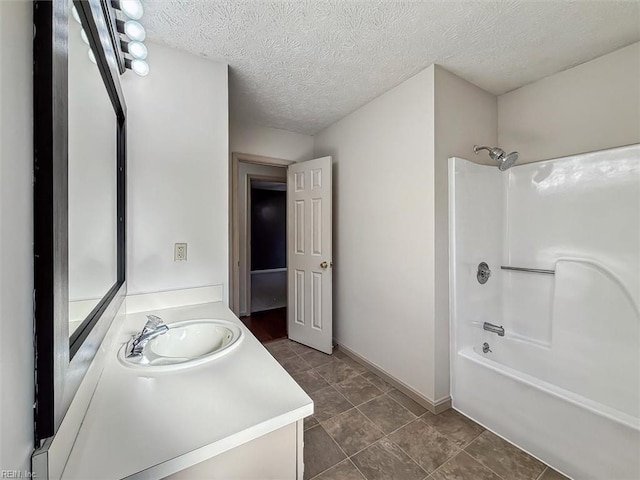 bathroom featuring baseboards, vanity, a textured ceiling, and bathing tub / shower combination