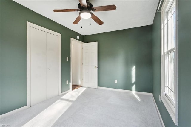 carpeted bedroom featuring a closet, multiple windows, ceiling fan, and baseboards