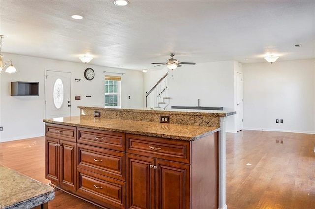 kitchen featuring dark wood-style floors, brown cabinetry, a kitchen island, and decorative light fixtures