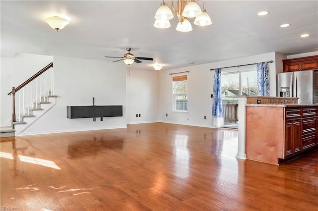 living room featuring recessed lighting, baseboards, stairway, dark wood-type flooring, and ceiling fan with notable chandelier