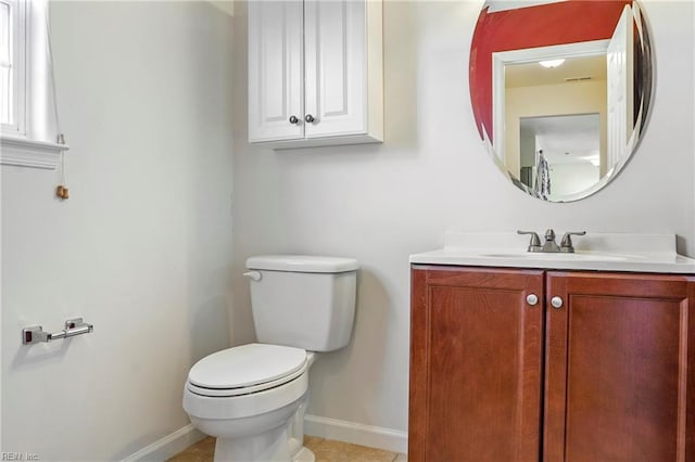 half bathroom with toilet, visible vents, vanity, baseboards, and tile patterned floors