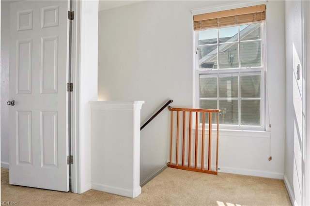 stairway with baseboards, a healthy amount of sunlight, and carpet flooring