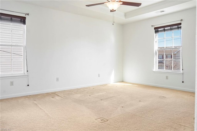 empty room with baseboards, visible vents, ceiling fan, a tray ceiling, and carpet flooring