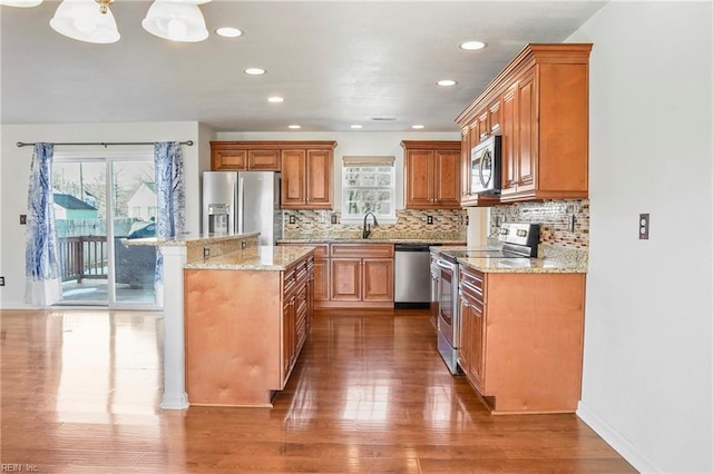 kitchen with appliances with stainless steel finishes, decorative backsplash, a kitchen island, and brown cabinets