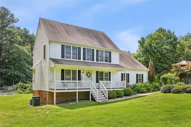 colonial inspired home featuring covered porch, roof with shingles, and a front yard