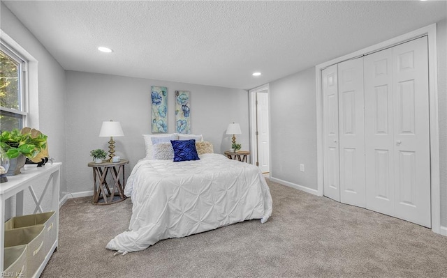 bedroom with baseboards, a textured ceiling, and light colored carpet