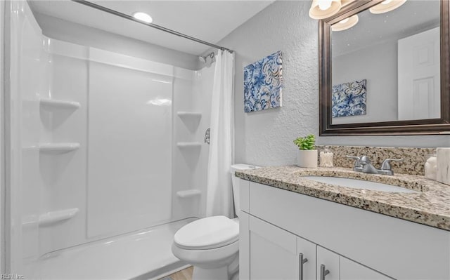 full bath featuring a shower with curtain, a textured wall, vanity, and toilet