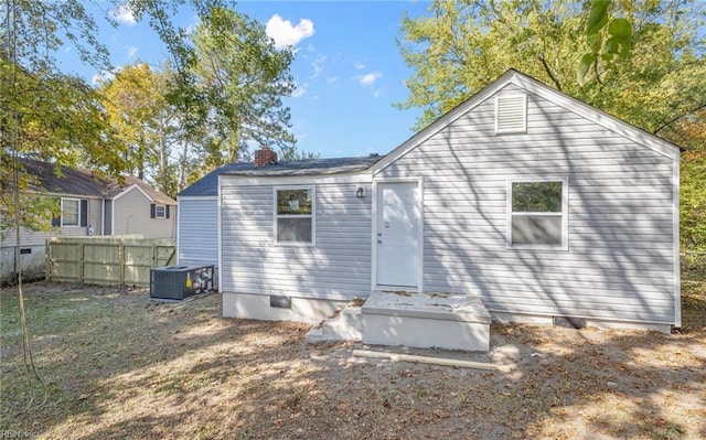 rear view of house featuring crawl space, a chimney, and fence