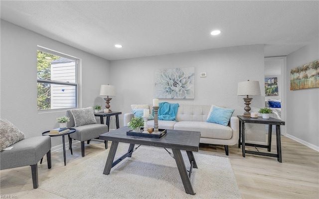 living room featuring light wood finished floors, baseboards, a textured ceiling, and recessed lighting