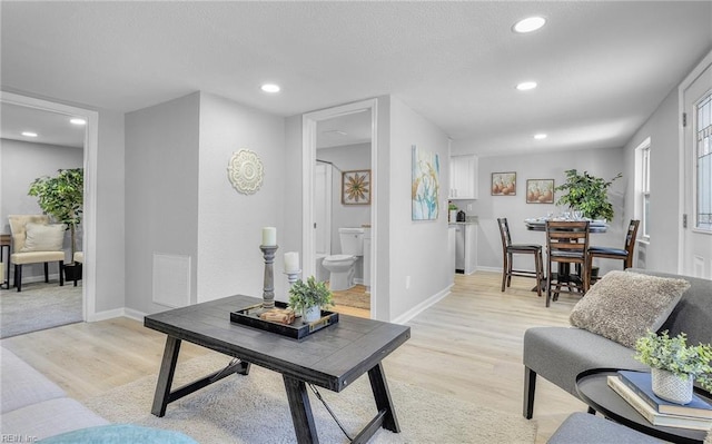 living room with light wood-style floors, recessed lighting, and baseboards