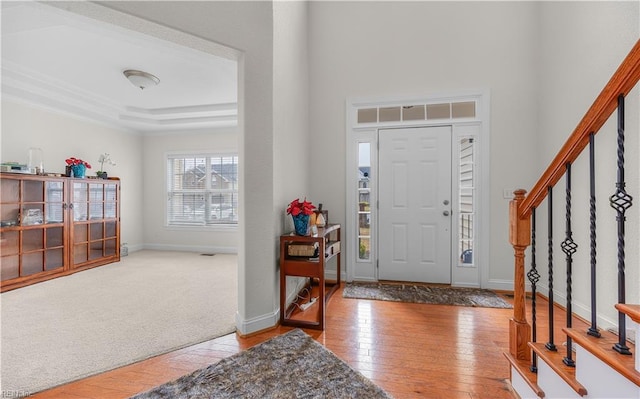 entrance foyer featuring stairs, light wood-type flooring, light carpet, and baseboards