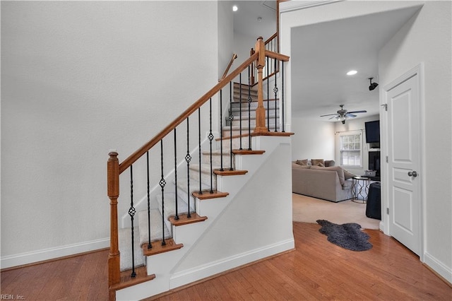 stairway with ceiling fan, wood finished floors, and baseboards