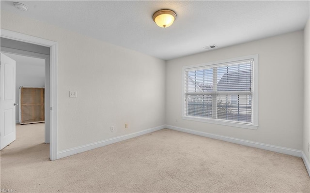 empty room featuring baseboards, visible vents, and light colored carpet