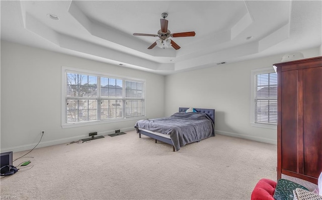 carpeted bedroom featuring ceiling fan, a tray ceiling, and baseboards