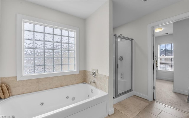 full bathroom with a jetted tub, a shower stall, baseboards, and tile patterned floors