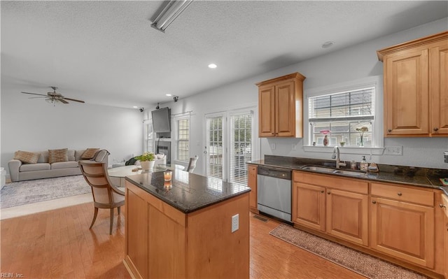 kitchen featuring a center island, stainless steel dishwasher, open floor plan, a sink, and light wood-type flooring