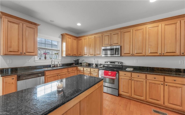 kitchen featuring visible vents, appliances with stainless steel finishes, dark stone counters, and a sink