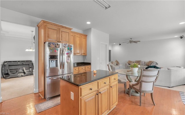 kitchen featuring open floor plan, ceiling fan, stainless steel refrigerator with ice dispenser, and a center island