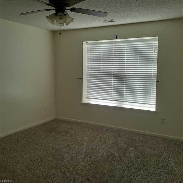 carpeted spare room featuring a ceiling fan, visible vents, a textured ceiling, and baseboards