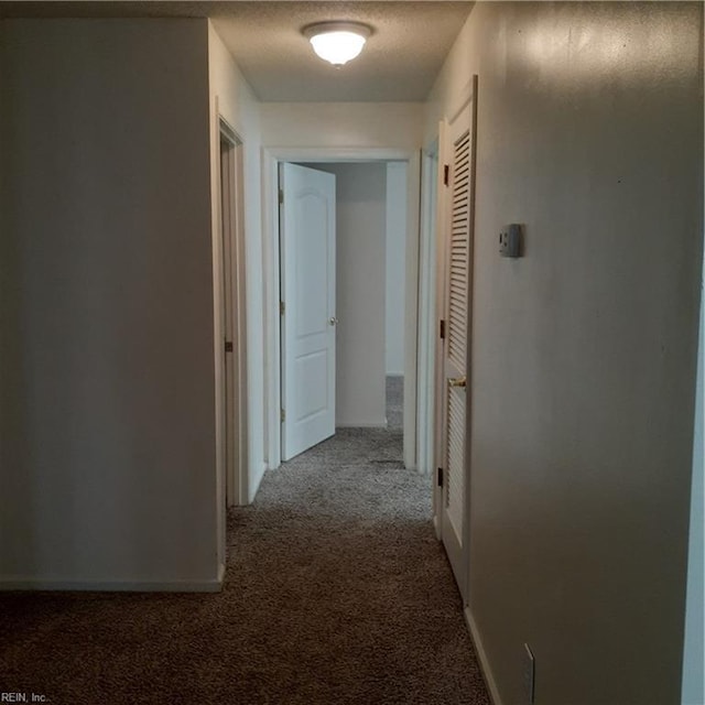 corridor with carpet and a textured ceiling