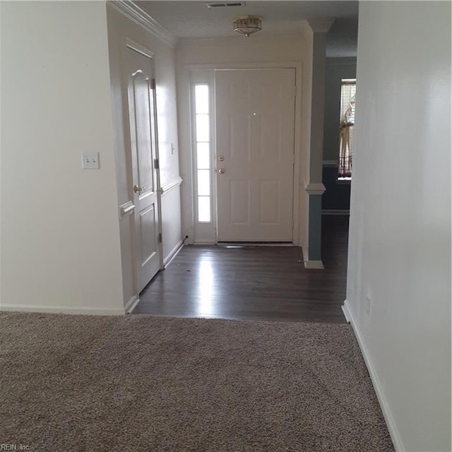 entrance foyer featuring dark carpet, a wealth of natural light, crown molding, and baseboards