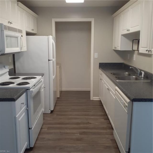 kitchen featuring white appliances, dark countertops, a sink, and white cabinets