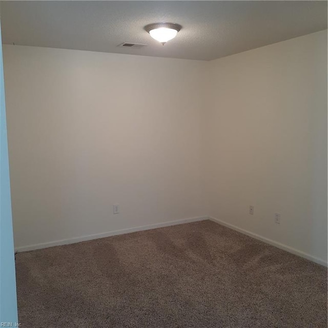 carpeted empty room with visible vents, a textured ceiling, and baseboards