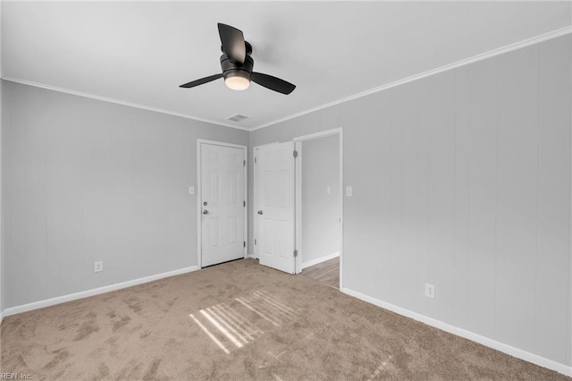 empty room featuring carpet, visible vents, crown molding, and baseboards