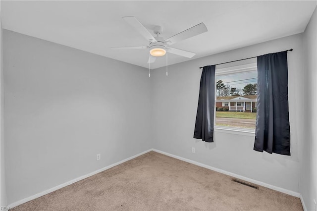 unfurnished room with carpet floors, visible vents, baseboards, and a ceiling fan