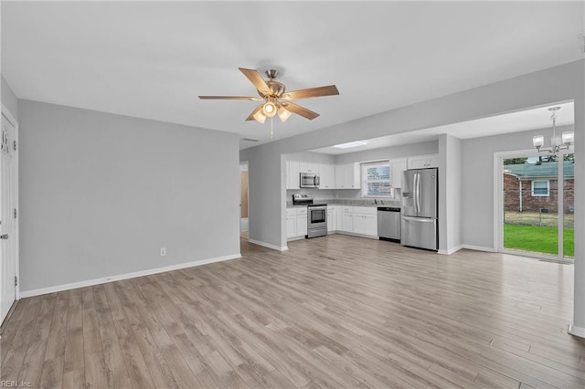 unfurnished living room with light wood-type flooring, baseboards, and ceiling fan with notable chandelier