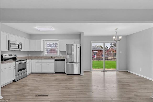 kitchen featuring visible vents, white cabinets, stainless steel appliances, light wood-type flooring, and a chandelier