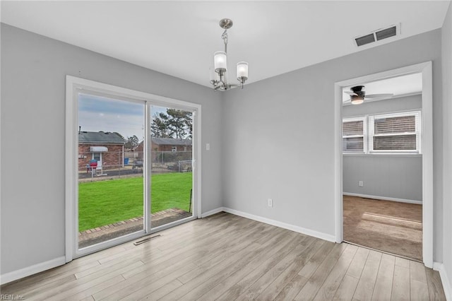 spare room featuring a wealth of natural light, visible vents, baseboards, and wood finished floors