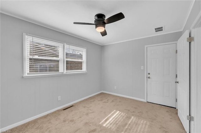 empty room with carpet, visible vents, and ornamental molding