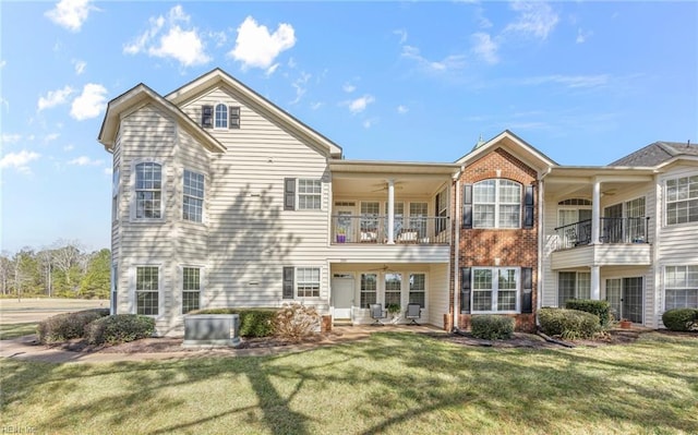 rear view of house featuring brick siding, a yard, a patio, central AC, and a balcony