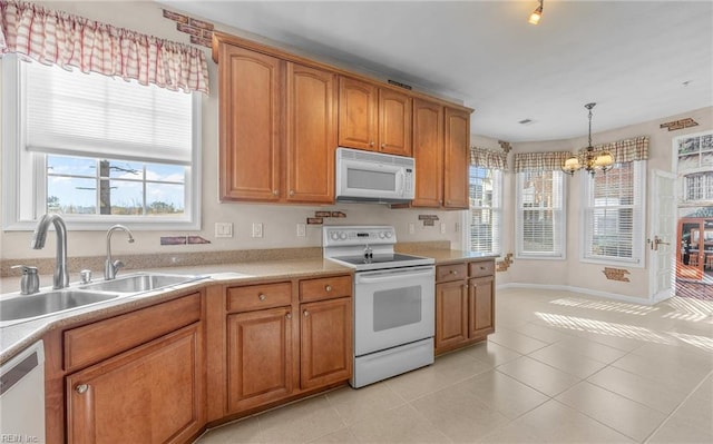 kitchen with white appliances, brown cabinetry, a sink, and light tile patterned flooring