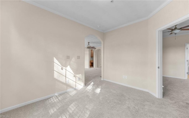 spare room with ornamental molding, arched walkways, carpet flooring, and a ceiling fan