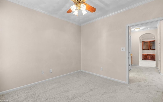 spare room featuring light carpet, ornamental molding, arched walkways, and baseboards