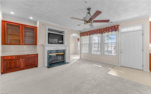 unfurnished living room with light carpet, a premium fireplace, baseboards, and crown molding